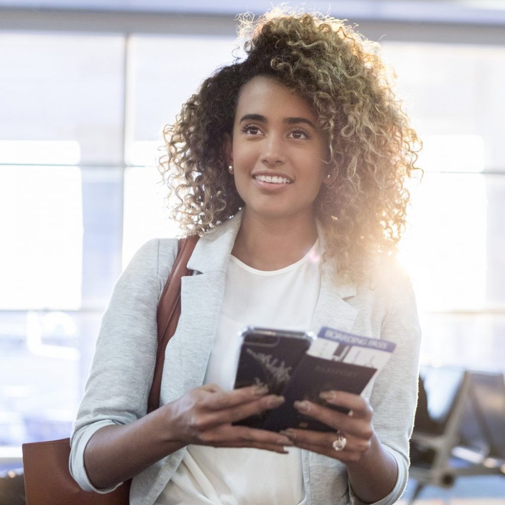 Young woman holding a passport while traveling, travel neck wallet concept