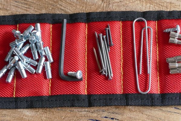 A red magnetic wristband with different small metal pieces stuck to each section.